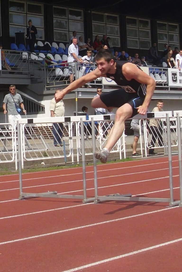 Atletický míting „Košice 2013“, GPS 4.mája Na trati 110 m prekážok Viliam Papšo z Banskej Bytrice, víťaz podujatia v kvalitnom čase 14.00 s, v pozadí na tribúne stojaci slovenský rekordér Igor Kováč (13,13 s), tretí z MS 1997 v Aténach (13,18 s)